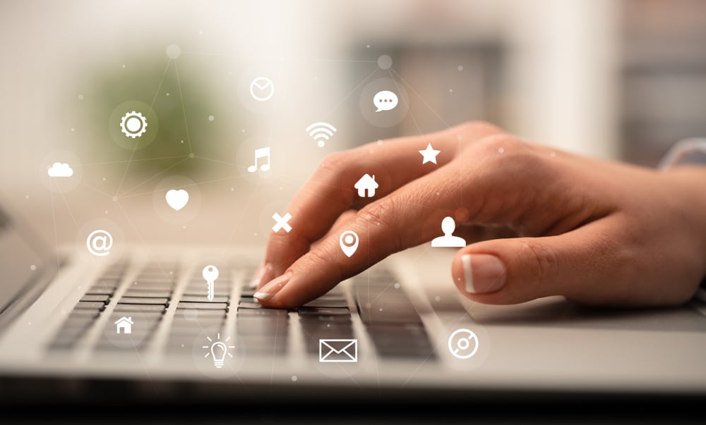 Business woman hand typing on keyboard with application icons around