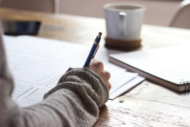 person writing on brown wooden table